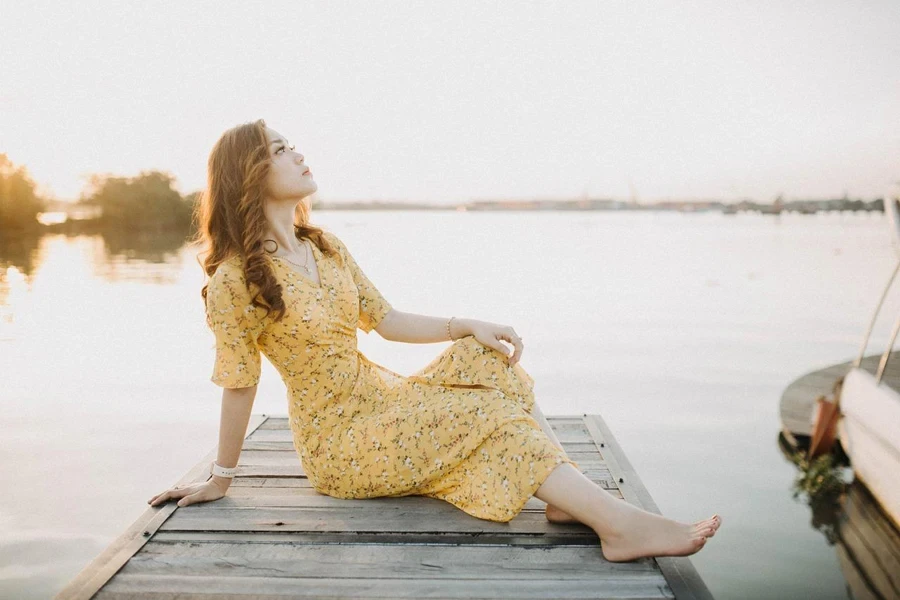 Woman in yellow floral midi dress sitting on a deck