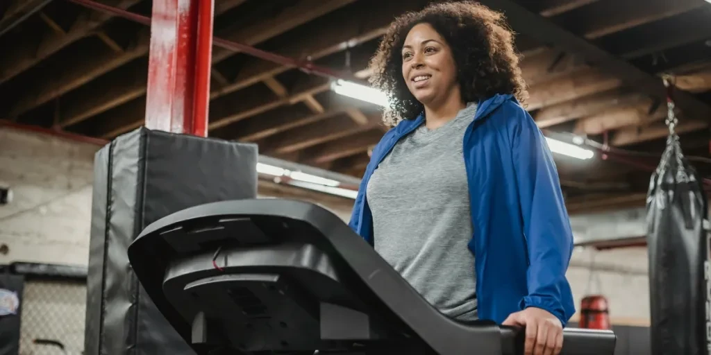 Woman smiling as she exercises on a treadmill, indoor gym environment