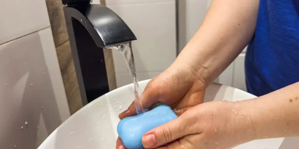 Woman washing hands under the faucet with soap in bathroom to prevent coronavirus infection