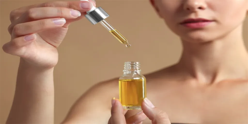 Femme avec un sérum cosmétique dans ses mains sur fond beige