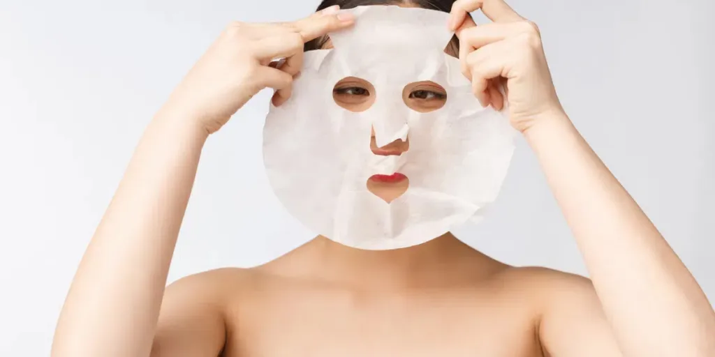 Woman with purifying mask on her face isolated on white background