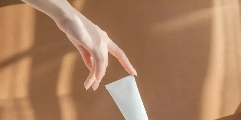 Woman's finger touches mock up of cream tube