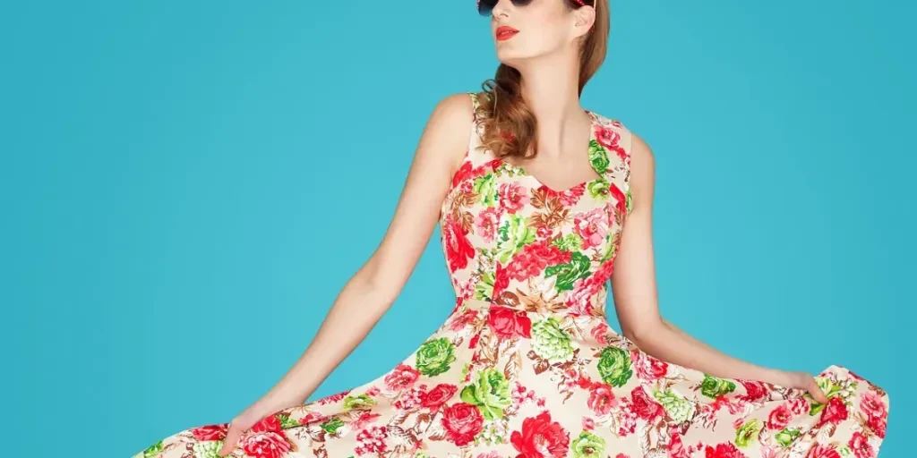 Young Caucasian woman in retro floral summer dress over blue background