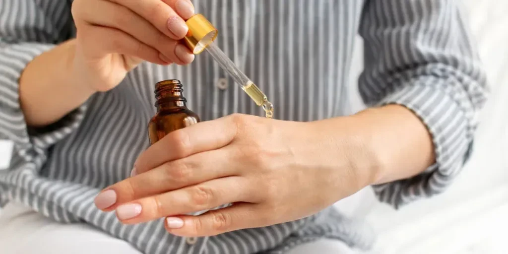 Young caucasian woman applies moisturizing nourishing oil on her hands close-up