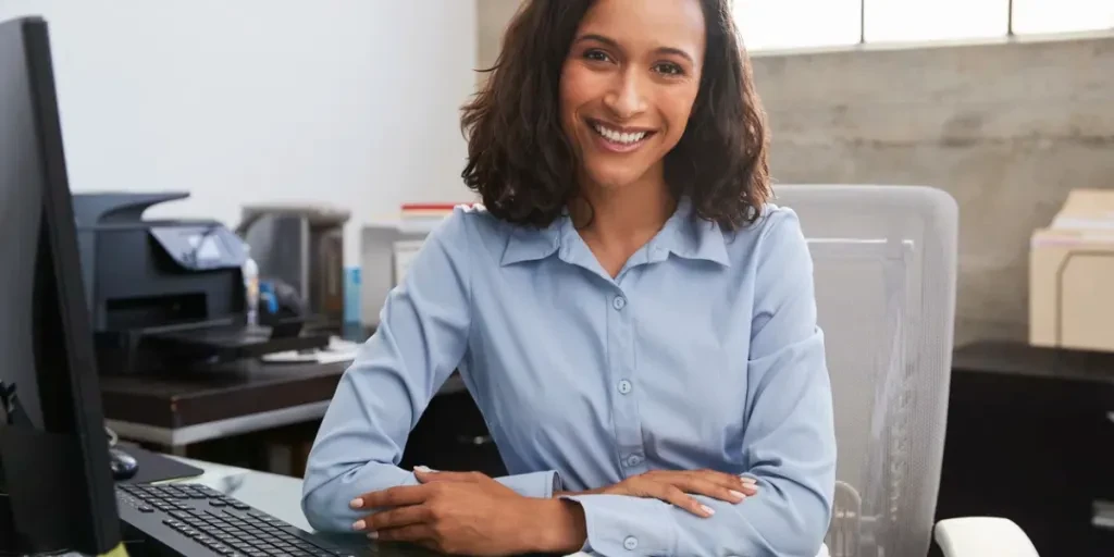 Young female professional at desk smiling to camera