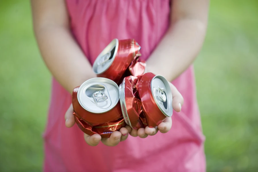 Young girl holding crushed cans