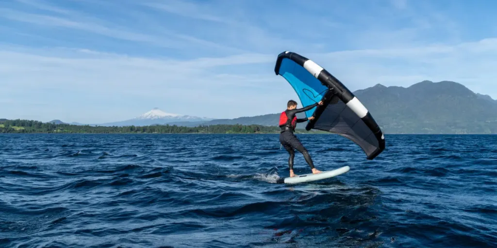 Junge Person lernt Wingfoiling auf dem See mit dem Vulkan im Hintergrund