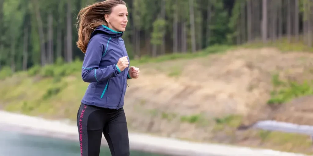 Young slim woman running on the road in the morning