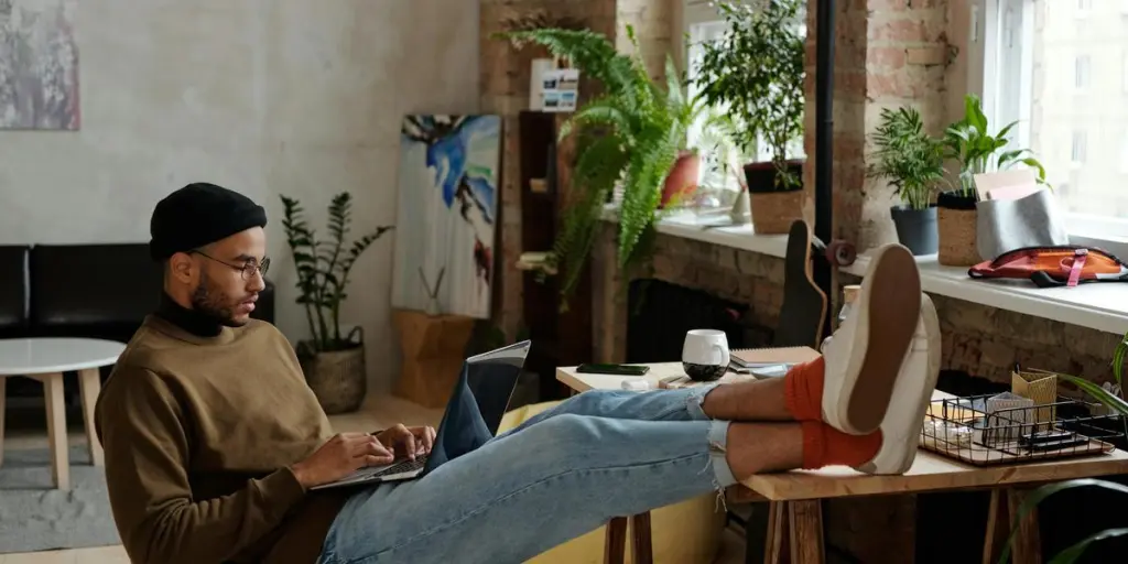 Un jeune homme élégant travaille sur un ordinateur portable dans un appartement urbain confortable. Configuration idéale pour le travail à distance