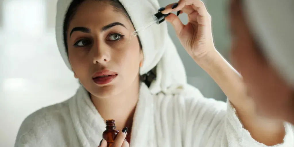 Young woman applying brightening face serum