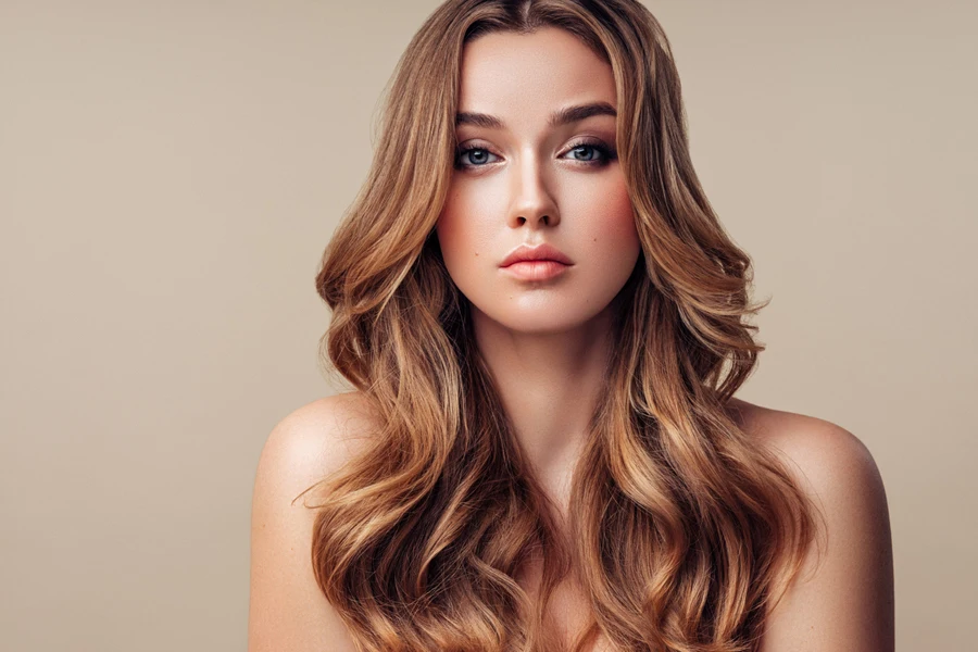 Young woman with wavy butterfly cut against beige wall