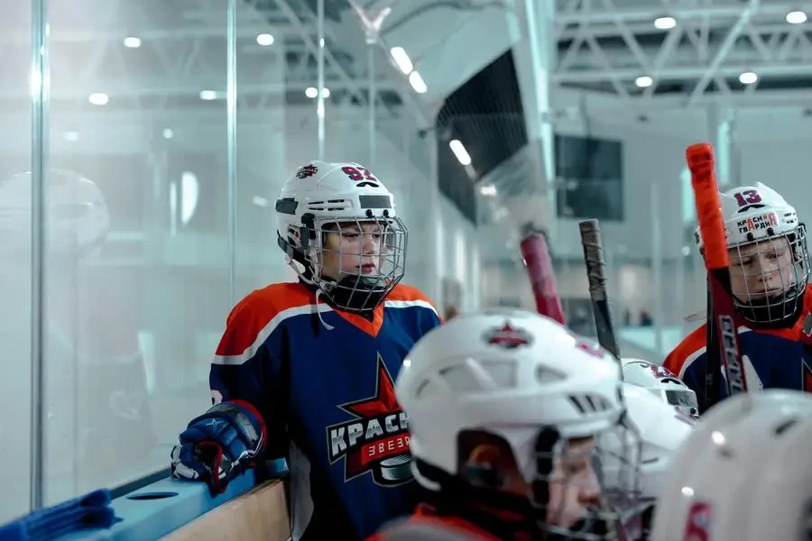 Youth hockey team players gather in the rink during a winter match, showcasing teamwork