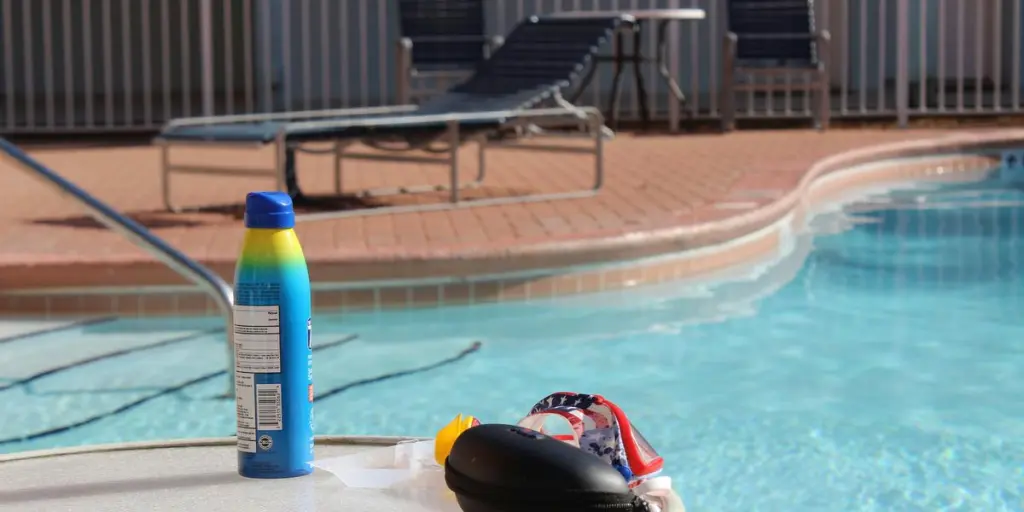 a bottle of sunscreen next to a swimming pool