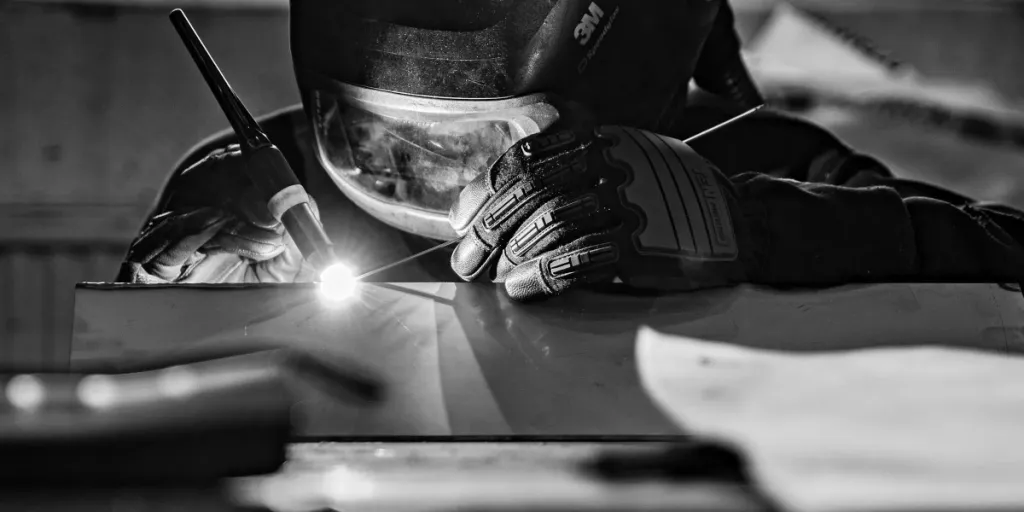 A man welds using a Heliarc welder