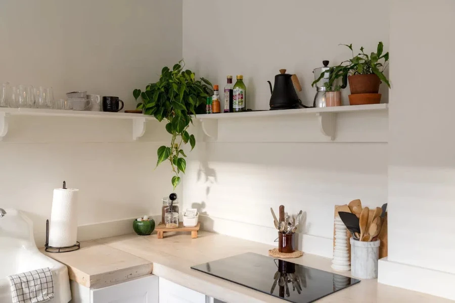 An electric stove on a kitchen counter surrounded with plants and kitchen utensils