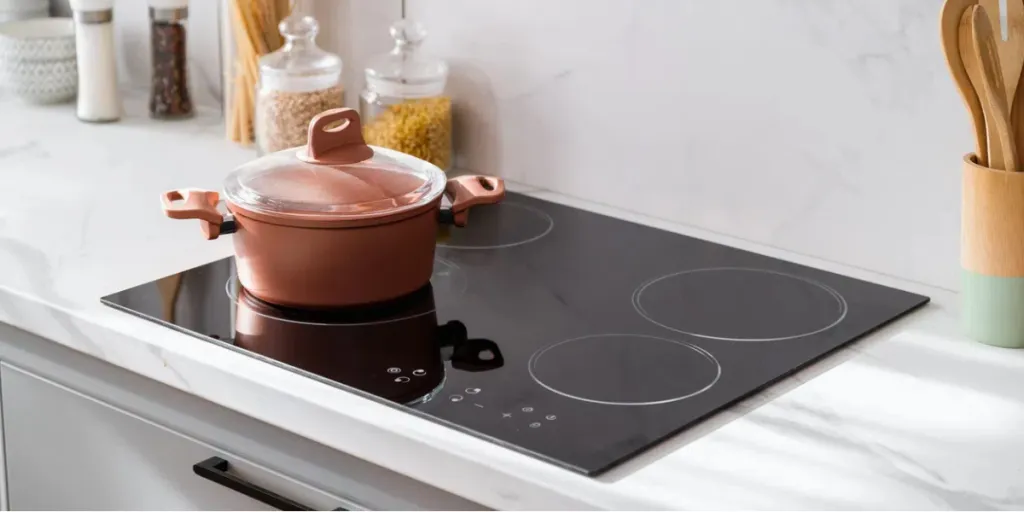 Clean black induction stove with control panel near marble countertop