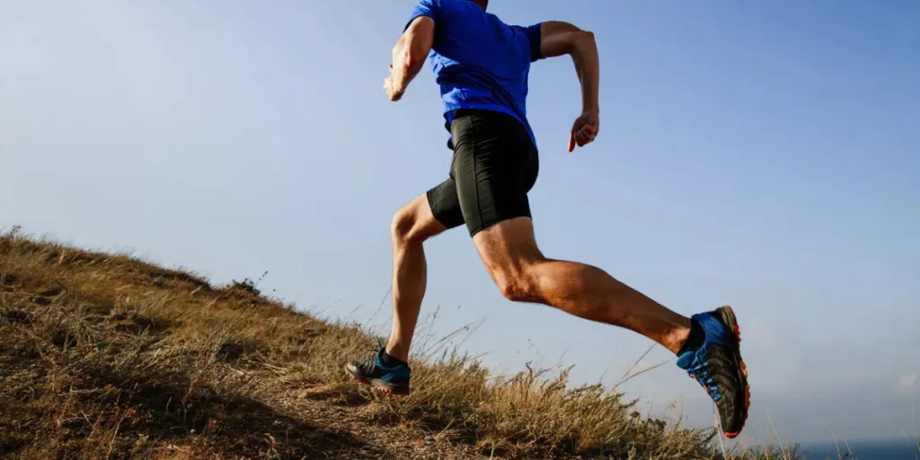 corsa dinamica in salita su sentiero atleta maschio corridore vista laterale