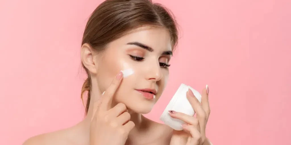 bella ragazza che applica la crema idratante dal tubetto sulla pelle