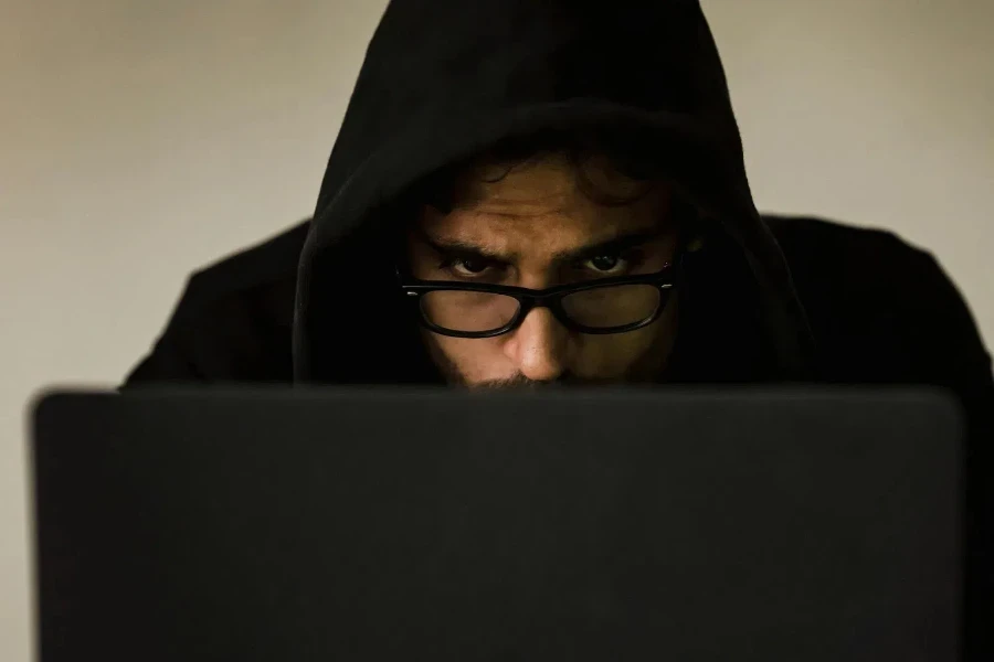 Hacker de capuz usando laptop