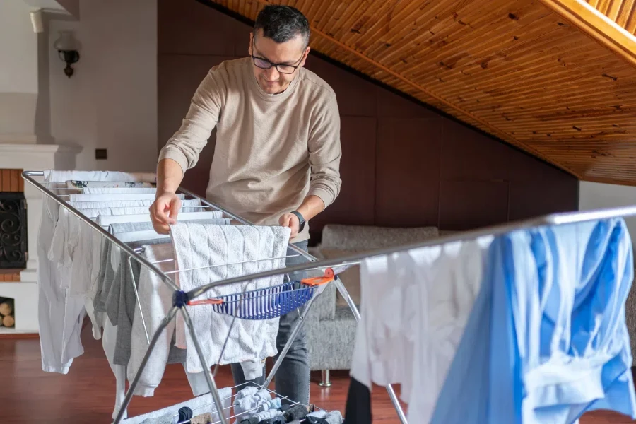 Uomo che asciuga i vestiti su uno stendino resistente