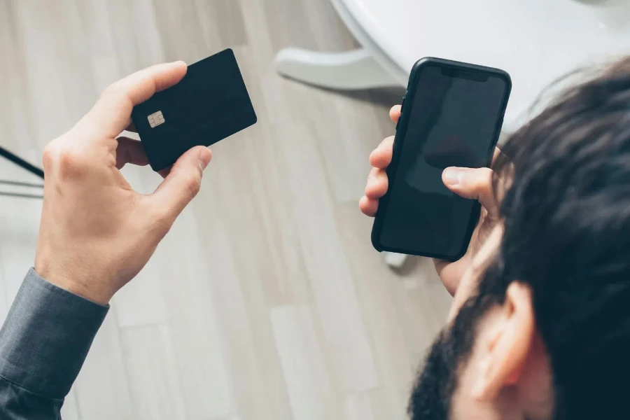 Homem segurando um smartphone preto