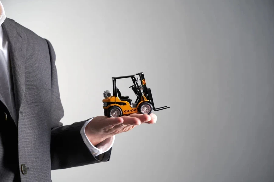 man holding toy forklift against gray background