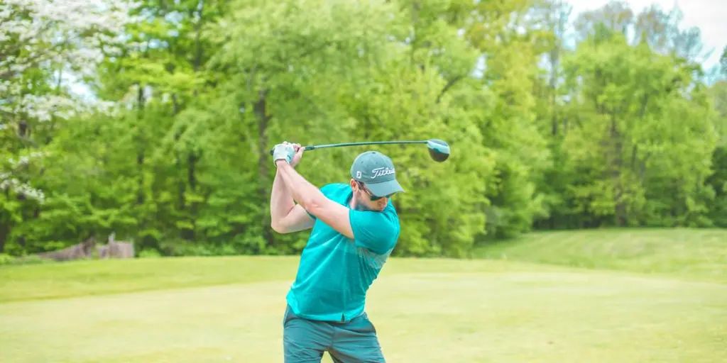 homem batendo bola de golfe