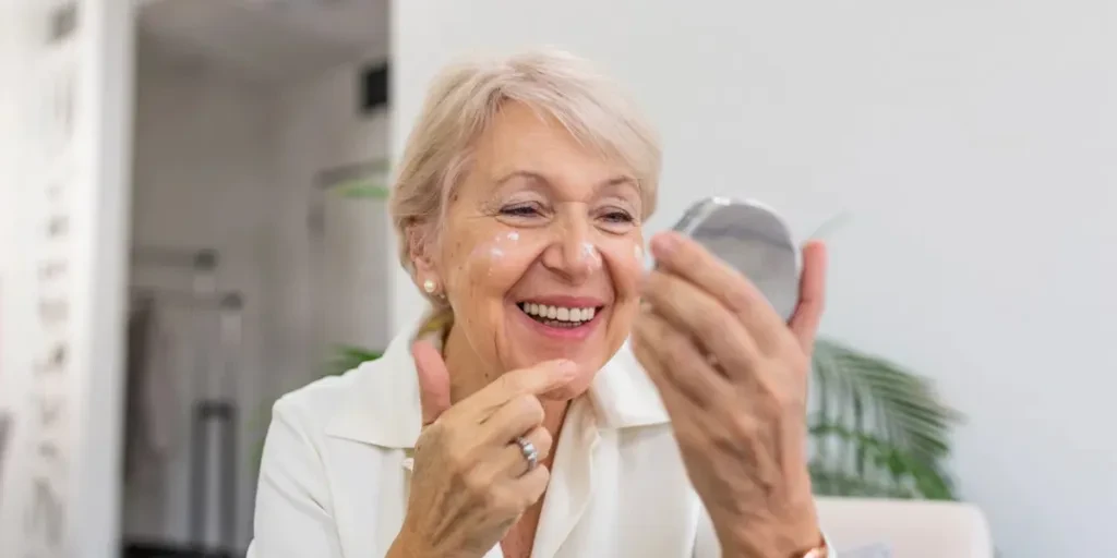 Mujer mayor tocándose la piel suave y perfecta de su rostro con los dedos