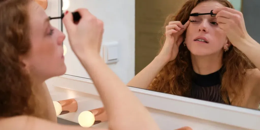 oung ballerina applying mascara, eyes make up in front of the mirror