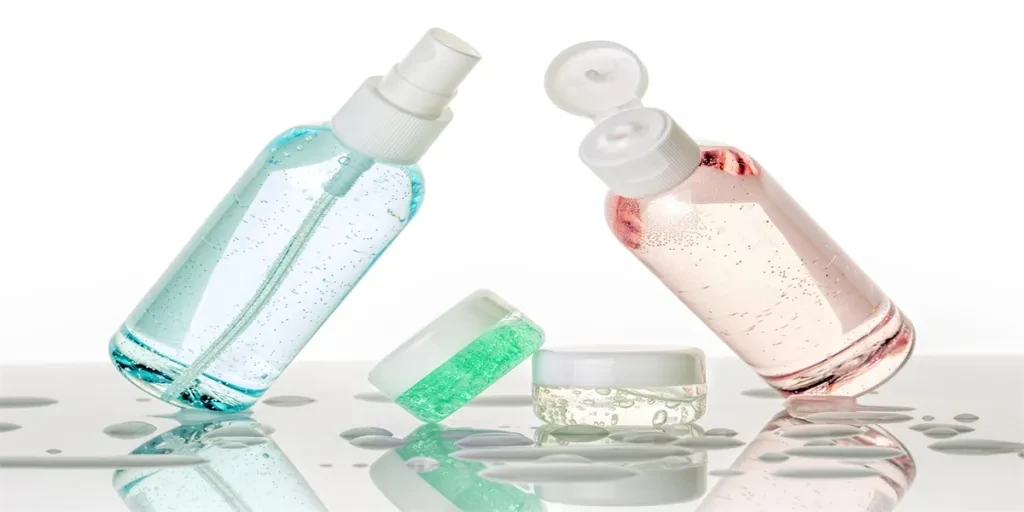 set of transparent toiletries and water droplets on white background