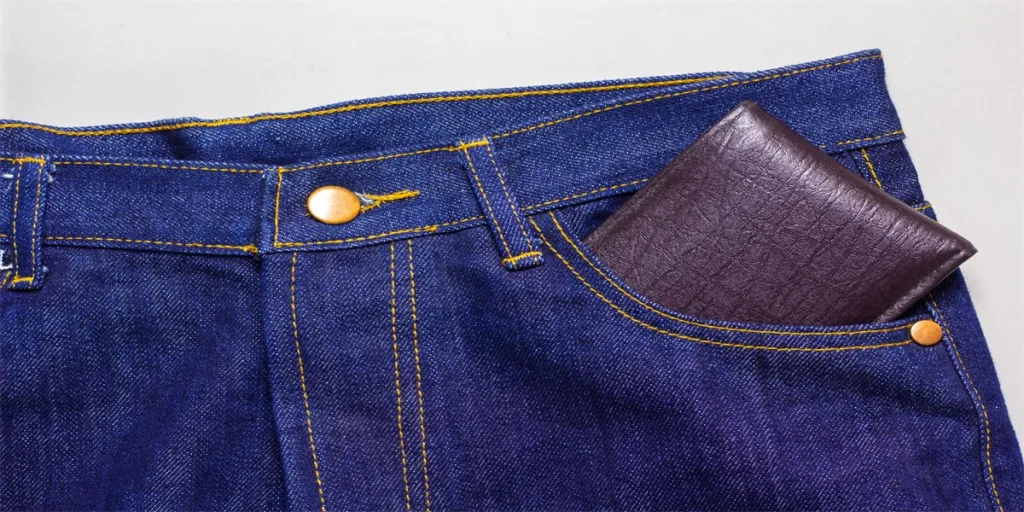 wallet in the front pocket of men jeans on grey background