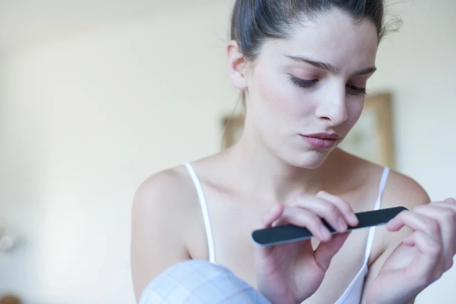 Mujer limándose las uñas para quitarse el esmalte de gel