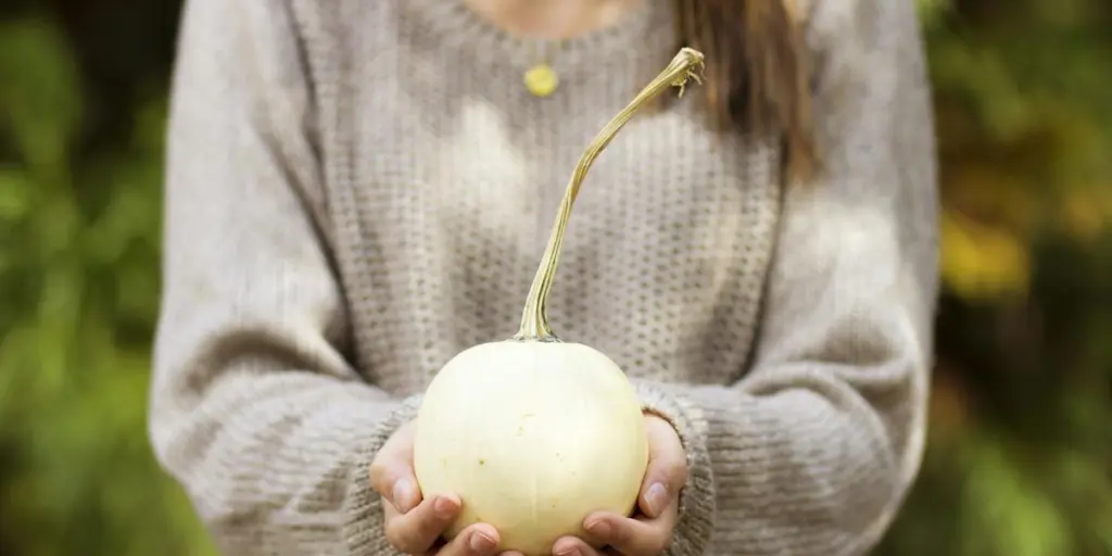 wanita memegang buah bulat putih di luar rumah