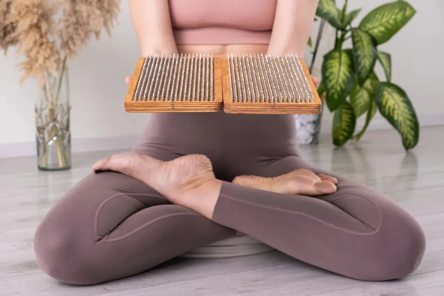 yogi woman holding wooden sadhu board for Nail standing practice yoga meditation foot massage