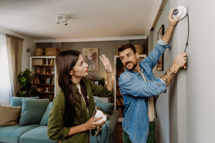 A couple installing CCTV cameras indoors