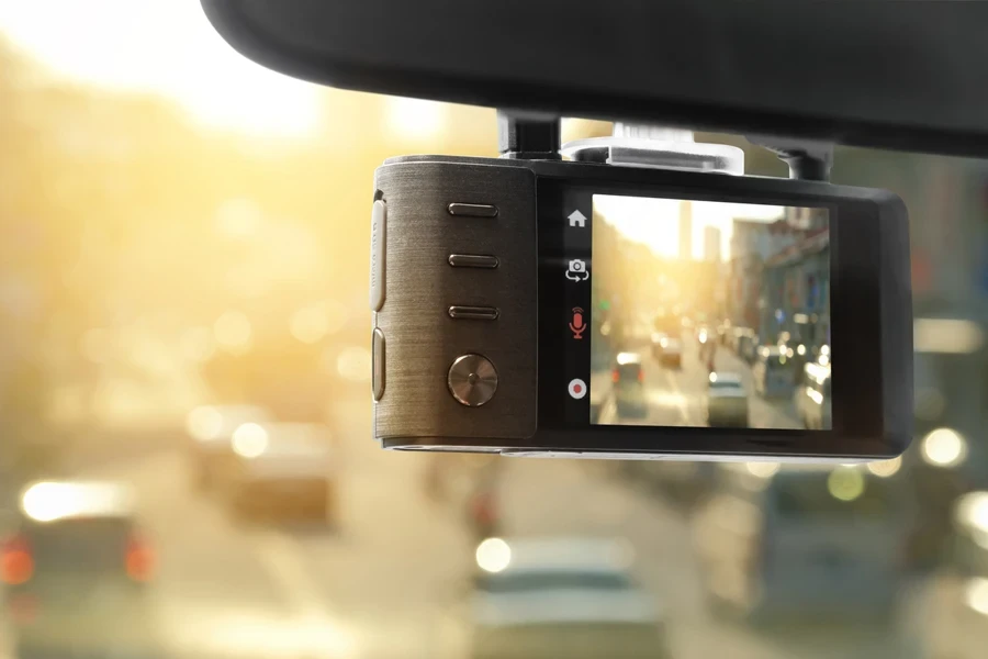 A dashcam on a car behind the rearview mirror