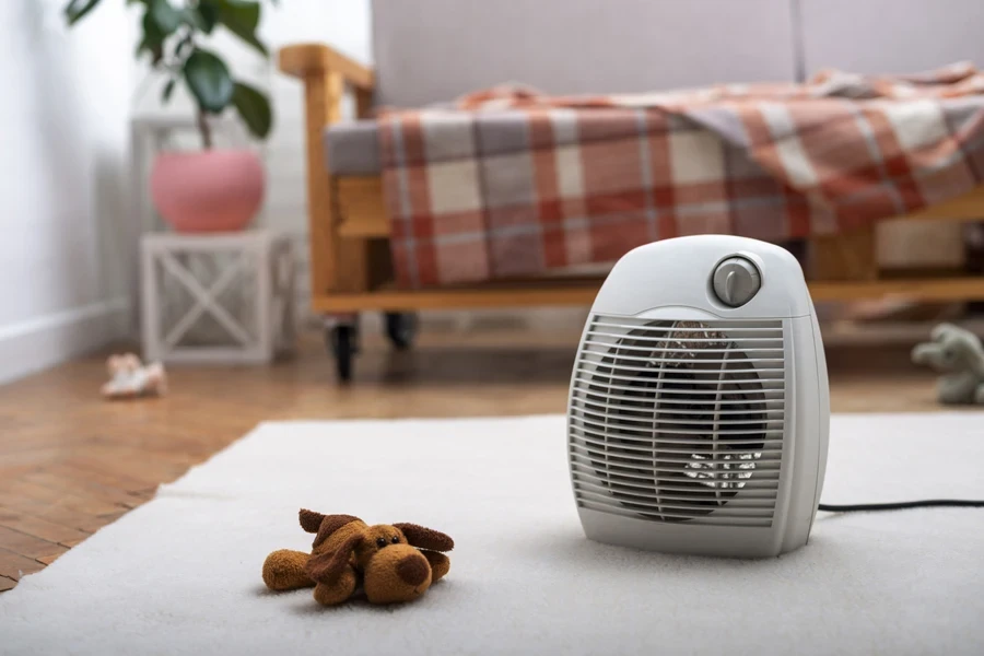 A fan on a carpet beside a bed.