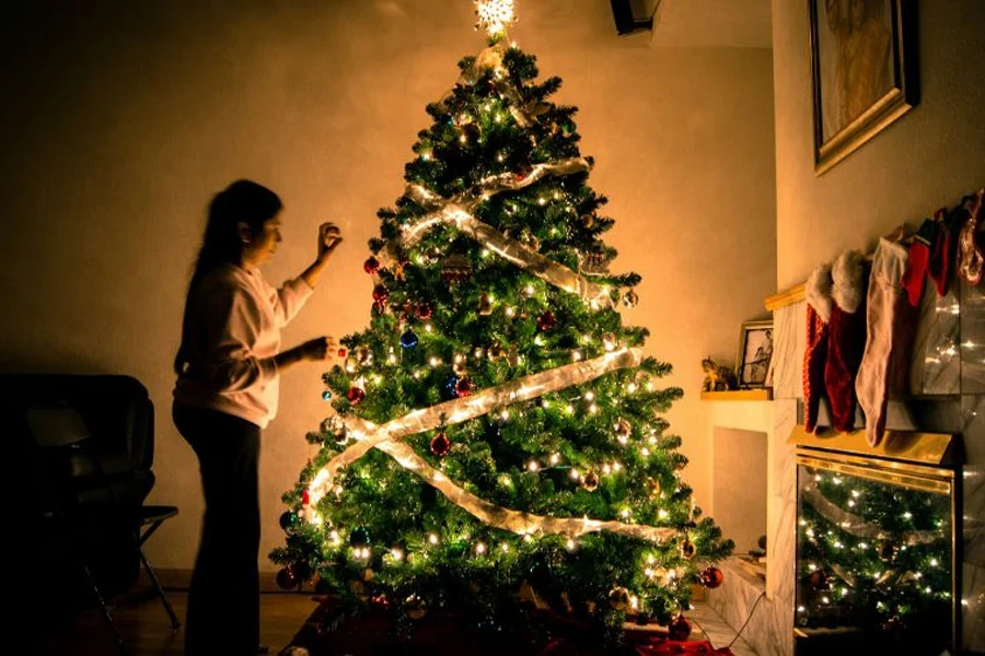 Una señora decorando un árbol de Navidad.