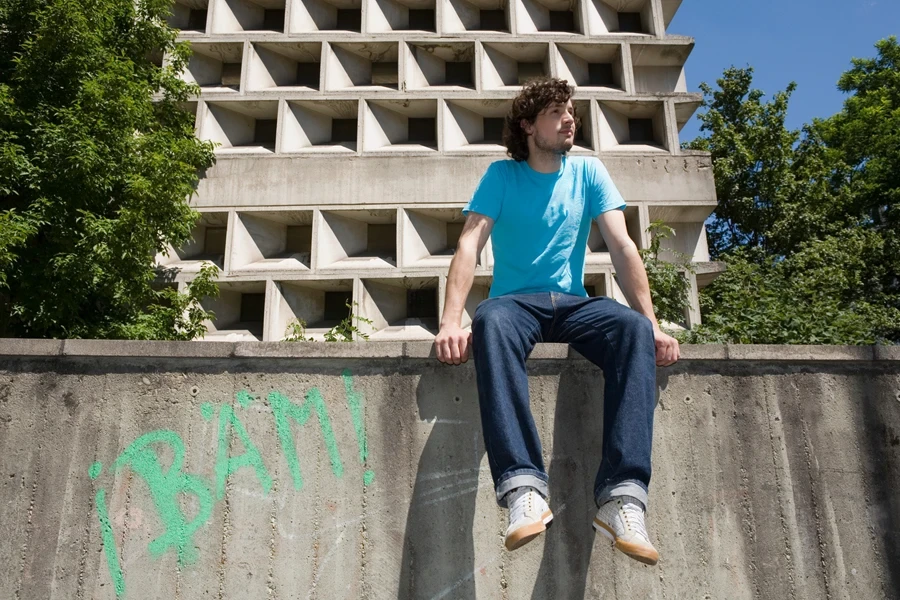 A man sitting on a wall in straight-leg loose jeans