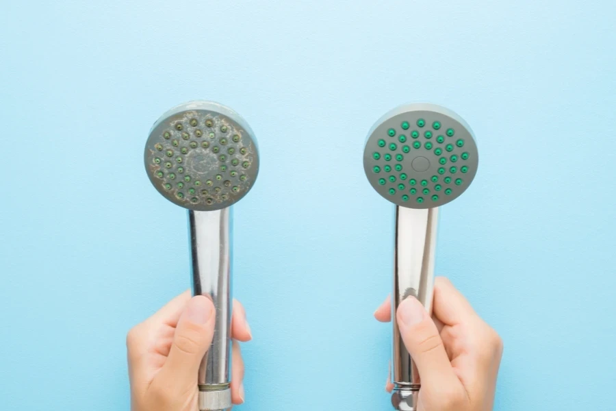 A person’s hands holding two types of shower heads