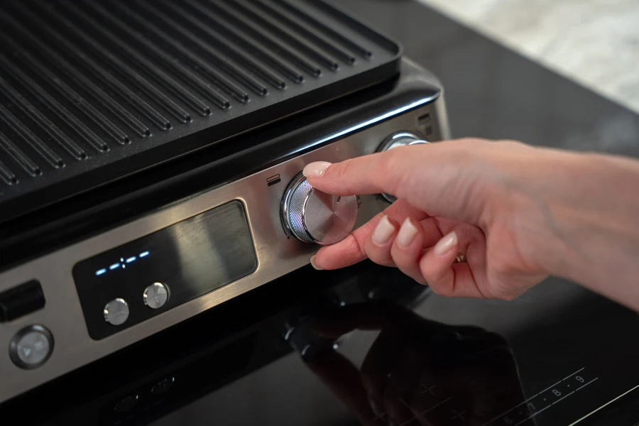 A woman turning on an electric barbeque grill