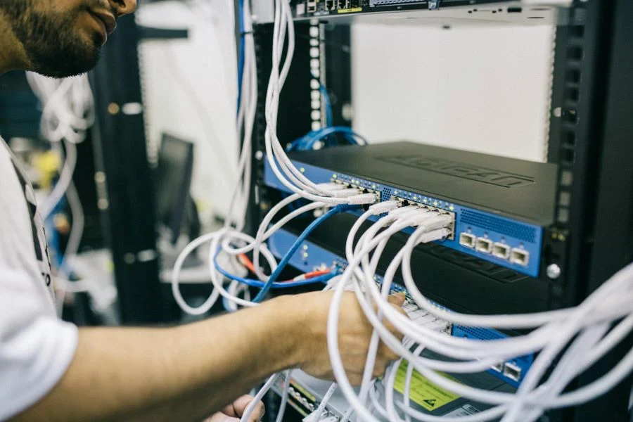 Un ingeniero arreglando cables en una sala de servidores.