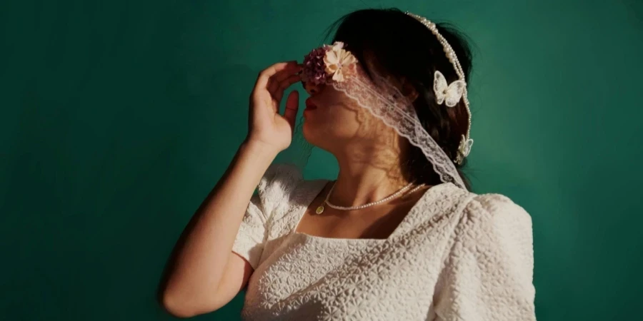 Portrait artistique d'une femme en robe blanche avec un bandeau floral sur les yeux