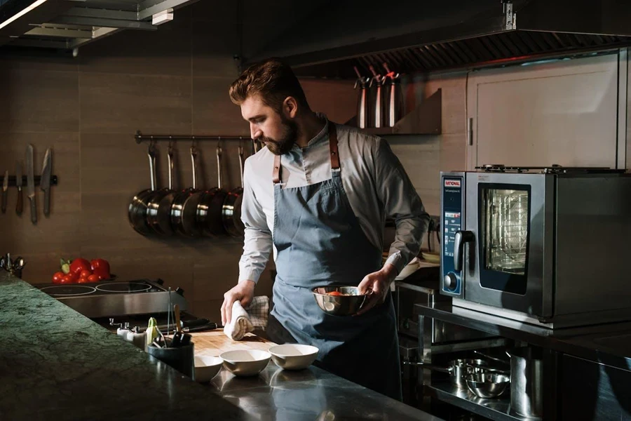 Chef in professional kitchen next to countertop oven