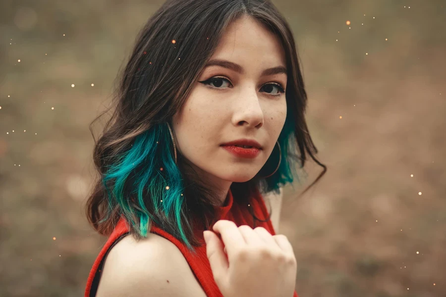 Close-up of a fashionable young woman with blue highlights posing outdoors