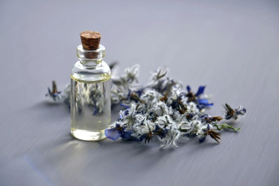 Close-up de um frasco de óleo de lavanda com flores secas para aromaterapia. Perfeito para temas de bem-estar