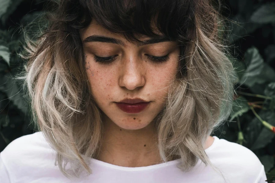 Close-up portrait of a young woman with freckles and two-toned hair outdoors