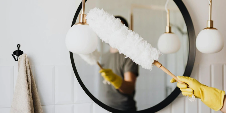 Crop woman dusting lamp during housework