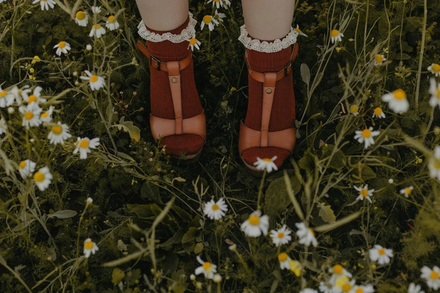 Menina no campo de flores durante o dia usando meias com babados