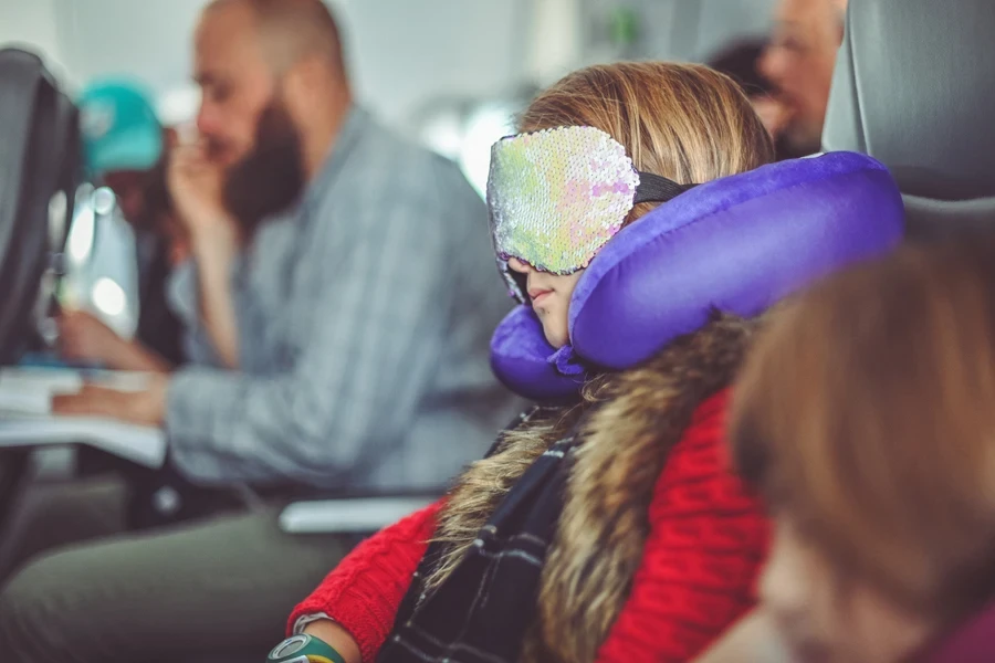 Girl on a plane with a travel neck pillow